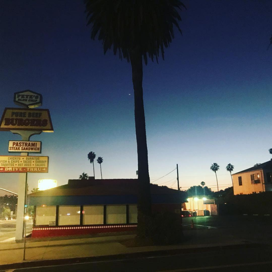 Pastrami shop under a palm tree at dusk
